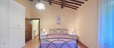 A bedroom with a bed, bedside tables, a wardrobe, and a ceiling fan.