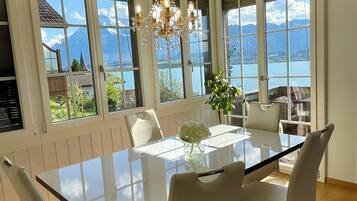 A dining area with a glass table, white chairs, and a chandelier.