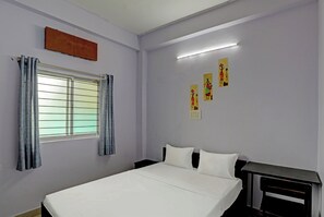 A bedroom with a bed, a window with curtains, a bedside table, and wall art. - Hotel O 815596 Hotel Sambodhi Palace (Bhopal)