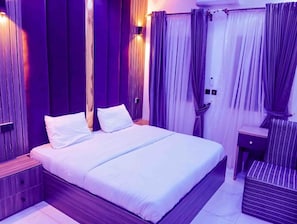 Una habitació amb un llit, una taula de nit i cortines.