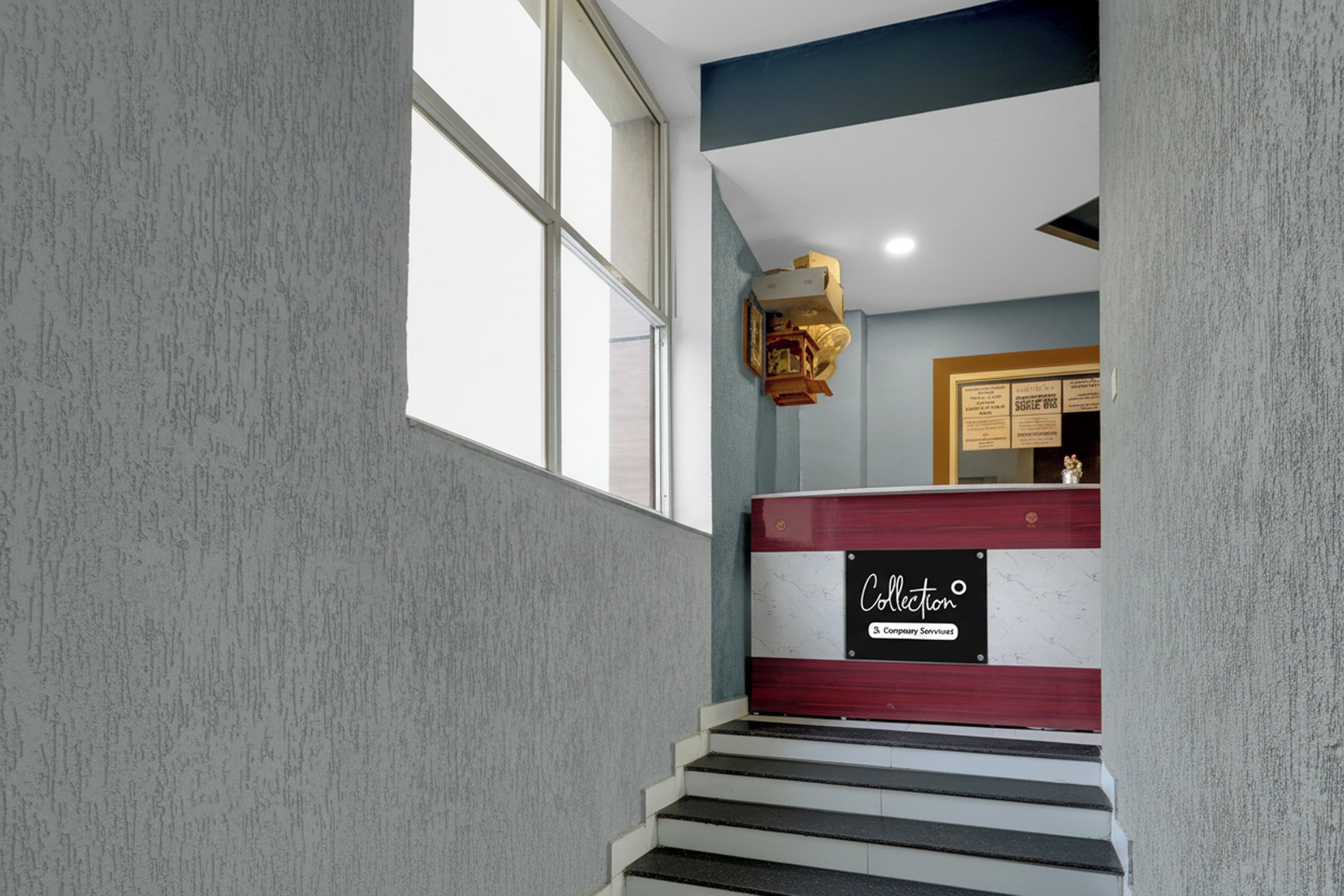 Una escalera con un cartel que dice 'Collection & Concierge Services' y un aviso enmarcado en la pared.