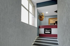Una escalera con un cartel que dice 'Collection & Concierge Services' y un aviso enmarcado en la pared.
