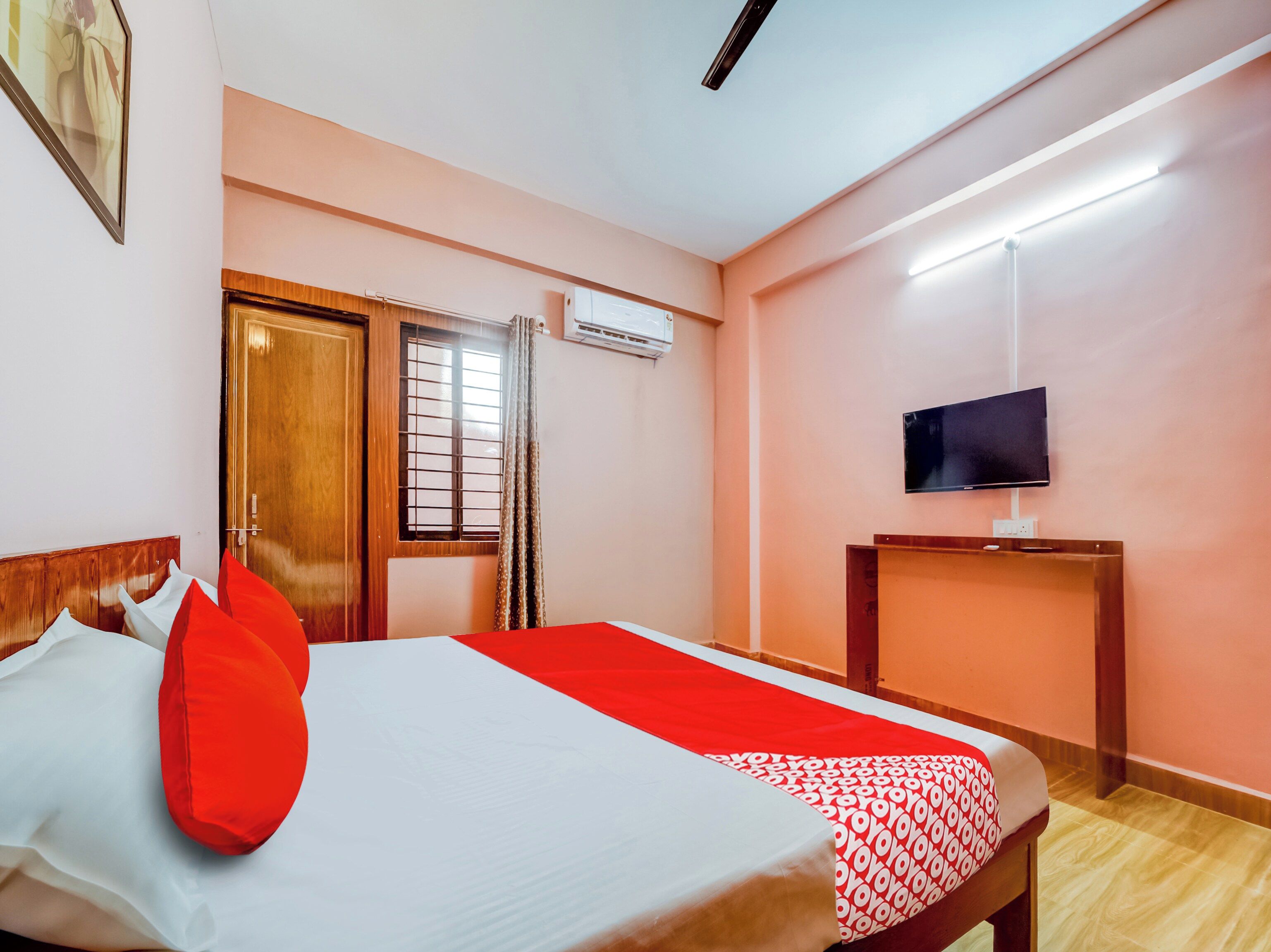 A hotel room with a bed, a television on a stand, and a window with curtains.