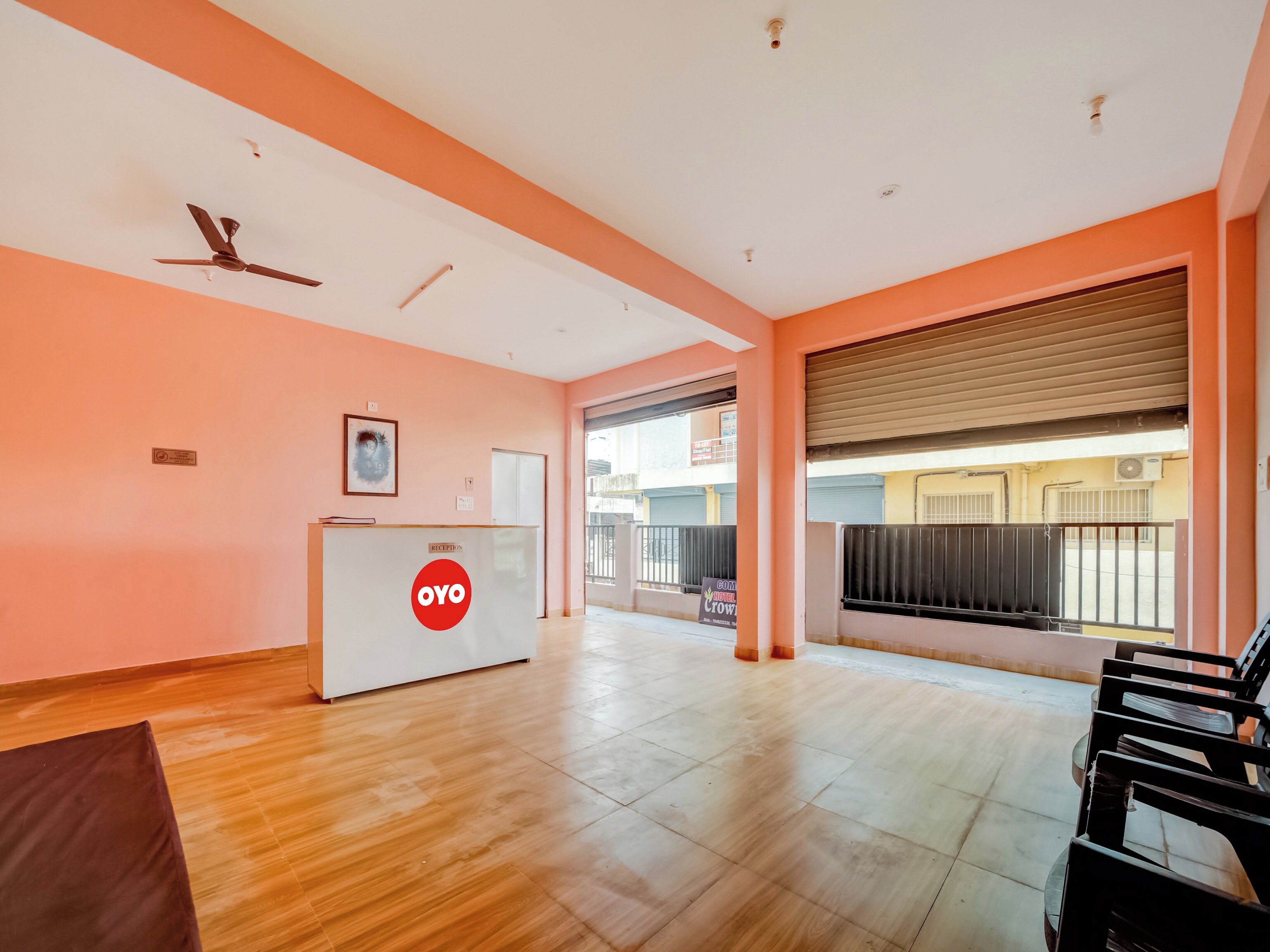 A reception area with a reception desk, a ceiling fan, and a view of the street outside.