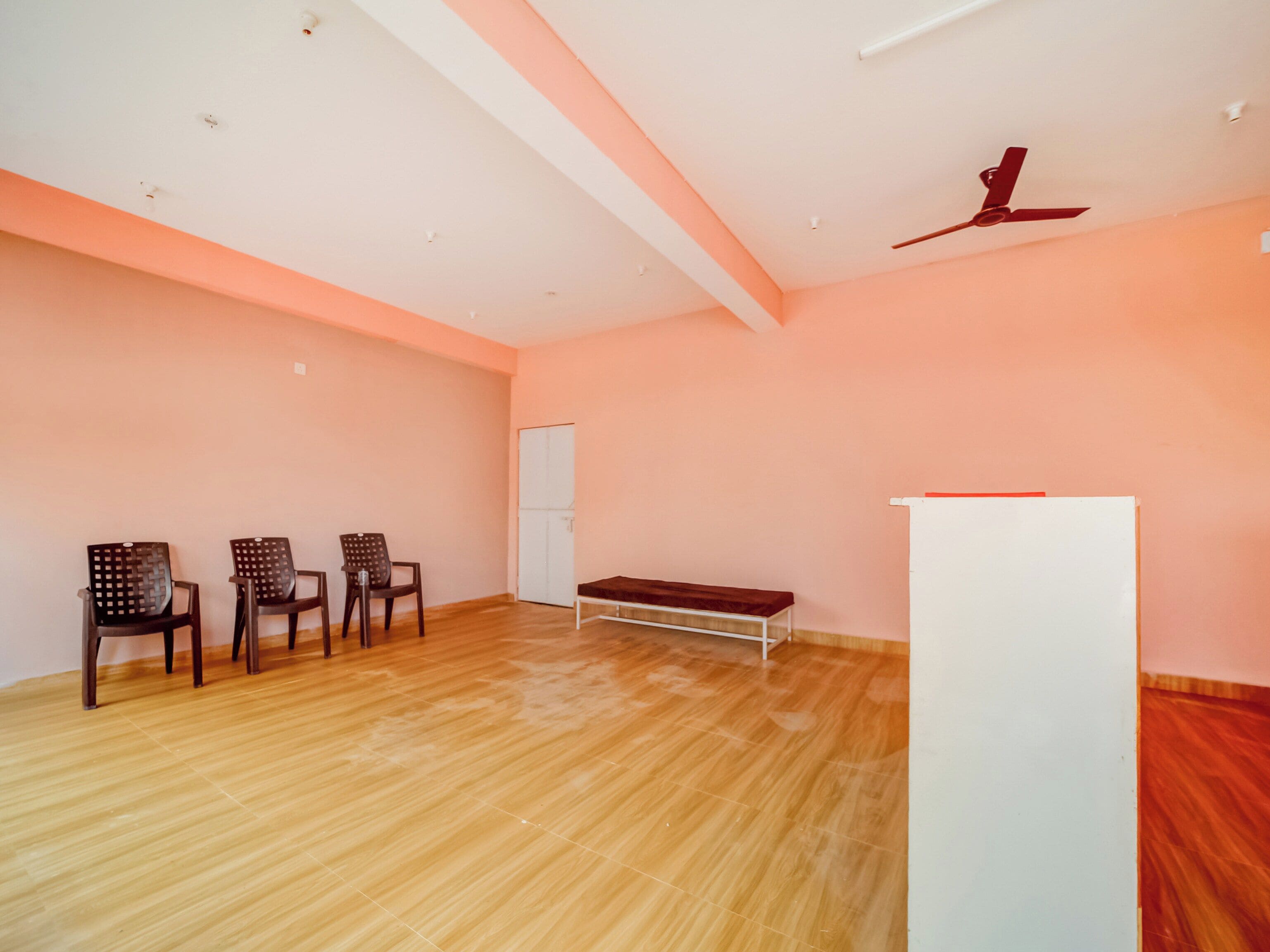 A room with a wooden floor, a white ceiling fan, and a white cabinet.