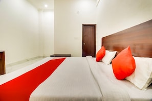 A hotel room with a bed, a wooden headboard, a red runner, and a door. - Hotel O Subham Residency (Bikaner)