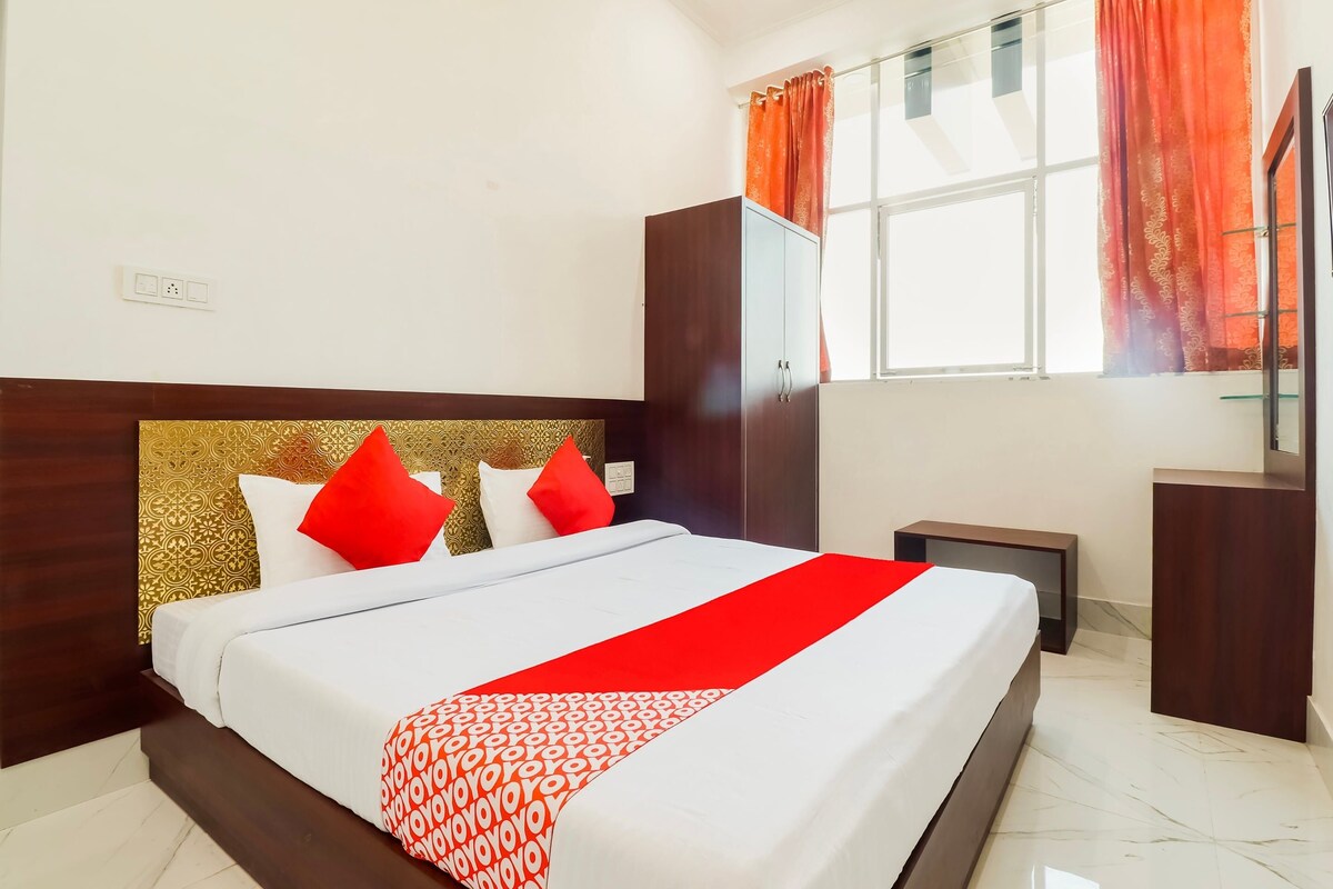 A hotel room with a bed, a wardrobe, a nightstand, and a window with curtains.