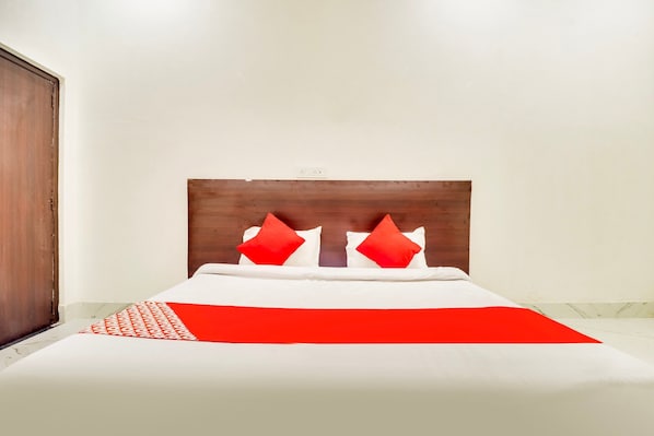 A bed with a wooden headboard, white bedding, and red pillows. - Hotel O Subham Residency (Bikaner)