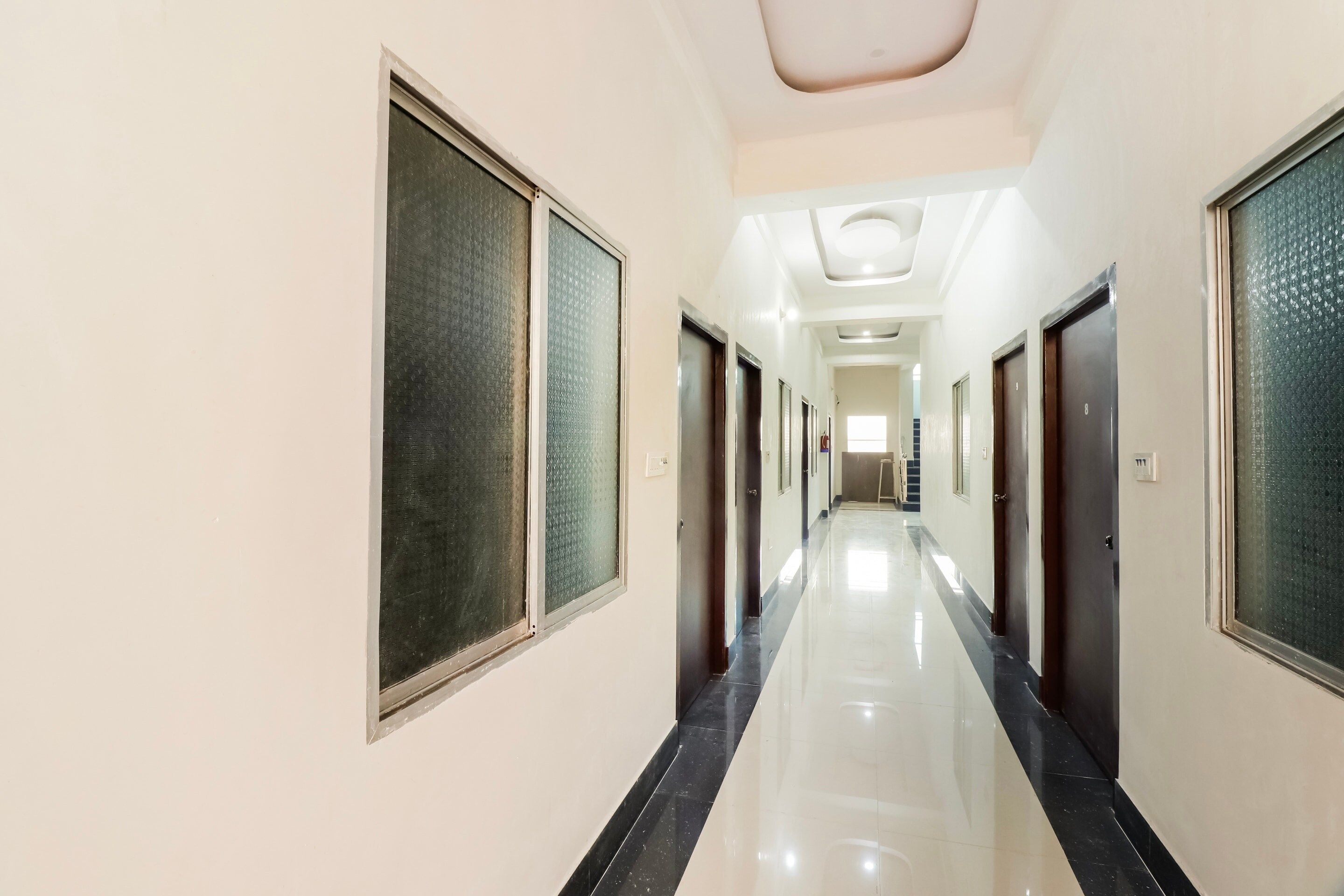 Un largo y estrecho pasillo de hotel con puertas a ambos lados, que conduce a habitaciones individuales.