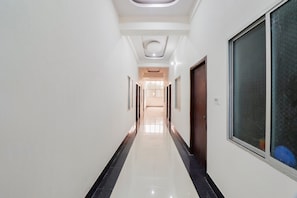 A corridor with white walls, a black-tiled floor, and doors on one side. - Hotel O Subham Residency (Bikaner)