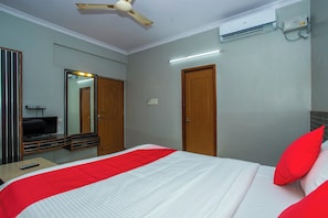 A hotel room with a bed, a ceiling fan, an air conditioning unit, a mirror, and a television. - Hotel O White Fort Near Lalbagh (Bangalore)