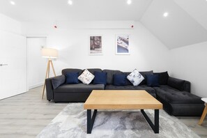 Un salon moderne avec un canapé gris foncé, une table basse en bois et un lampadaire.