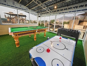 Un área de recreación interior con mesa de billar y futbolín.