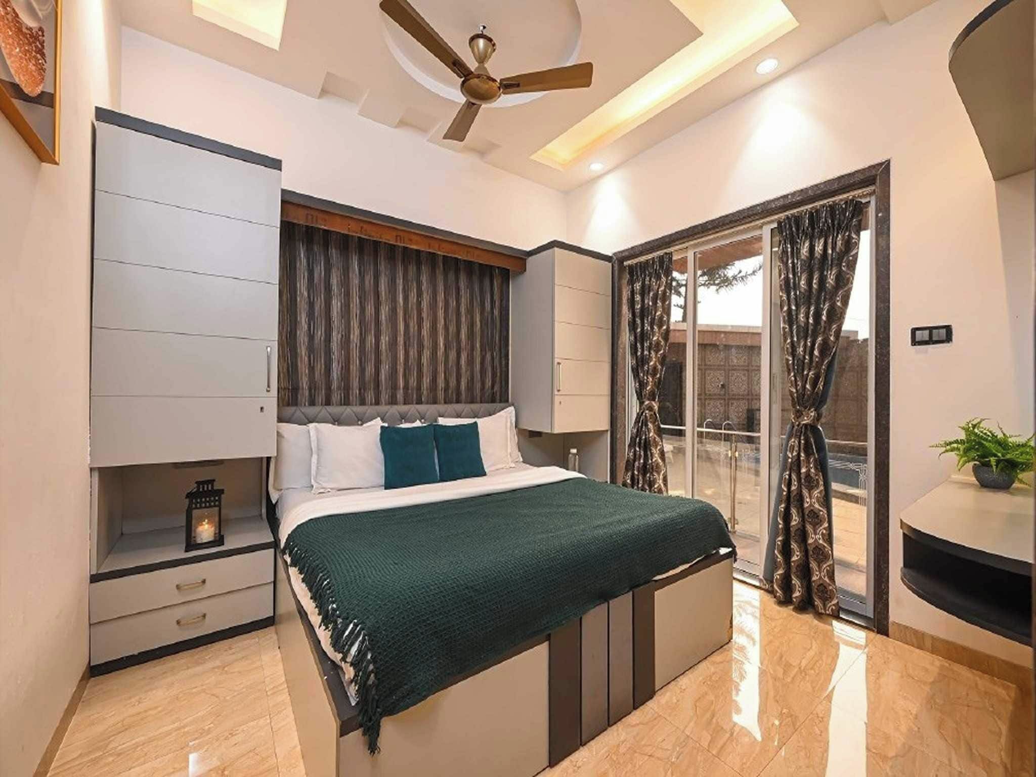 Un dormitorio moderno con una cama, ventilador de techo, mesita de noche y puerta corrediza de vidrio que da a un espacio exterior.