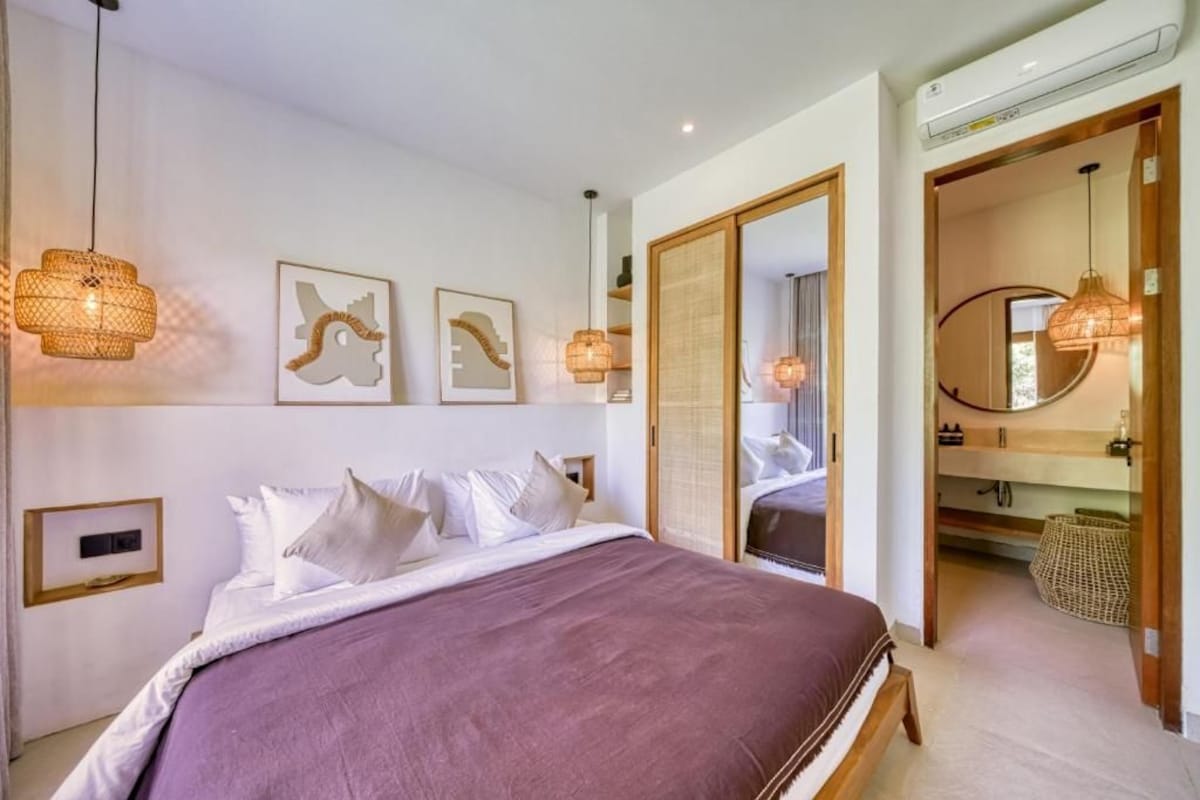A modern bedroom with a large bed, wall-mounted artwork, and a walk-in closet.