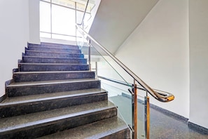A staircase with a glass railing and metal handrail. - Palette Hotel by CheckIn Zero Mile (Nagpur)