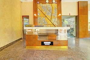 A reception desk with a 'RECEPTION' sign, a 'PALETTE' sign, and a wall with a map design. - Palette Hotel by CheckIn Zero Mile (Nagpur)