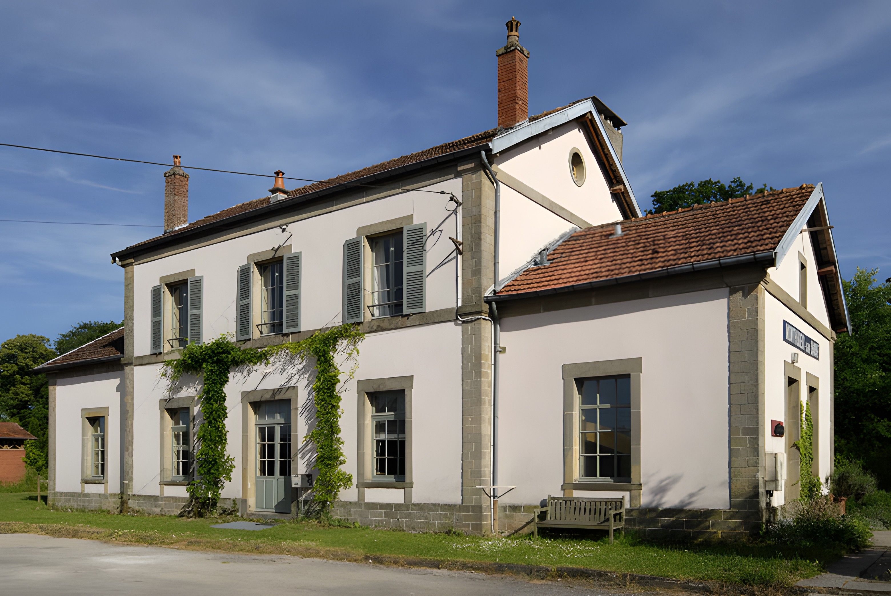 A two-story building with a symmetrical facade, featuring a central entrance with a door and windows on either side.