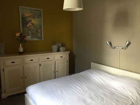A bedroom with a bed, a dresser, a wall-mounted lamp, and a poster. - L'Ancienne Gare Des Vosges (Monthureux-sur-Saône)