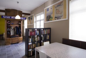 A library with bookshelves, a table, and a passageway labeled 'PASSAGE INTERPUBLIC.' - L'Ancienne Gare Des Vosges (Monthureux-sur-Saône)