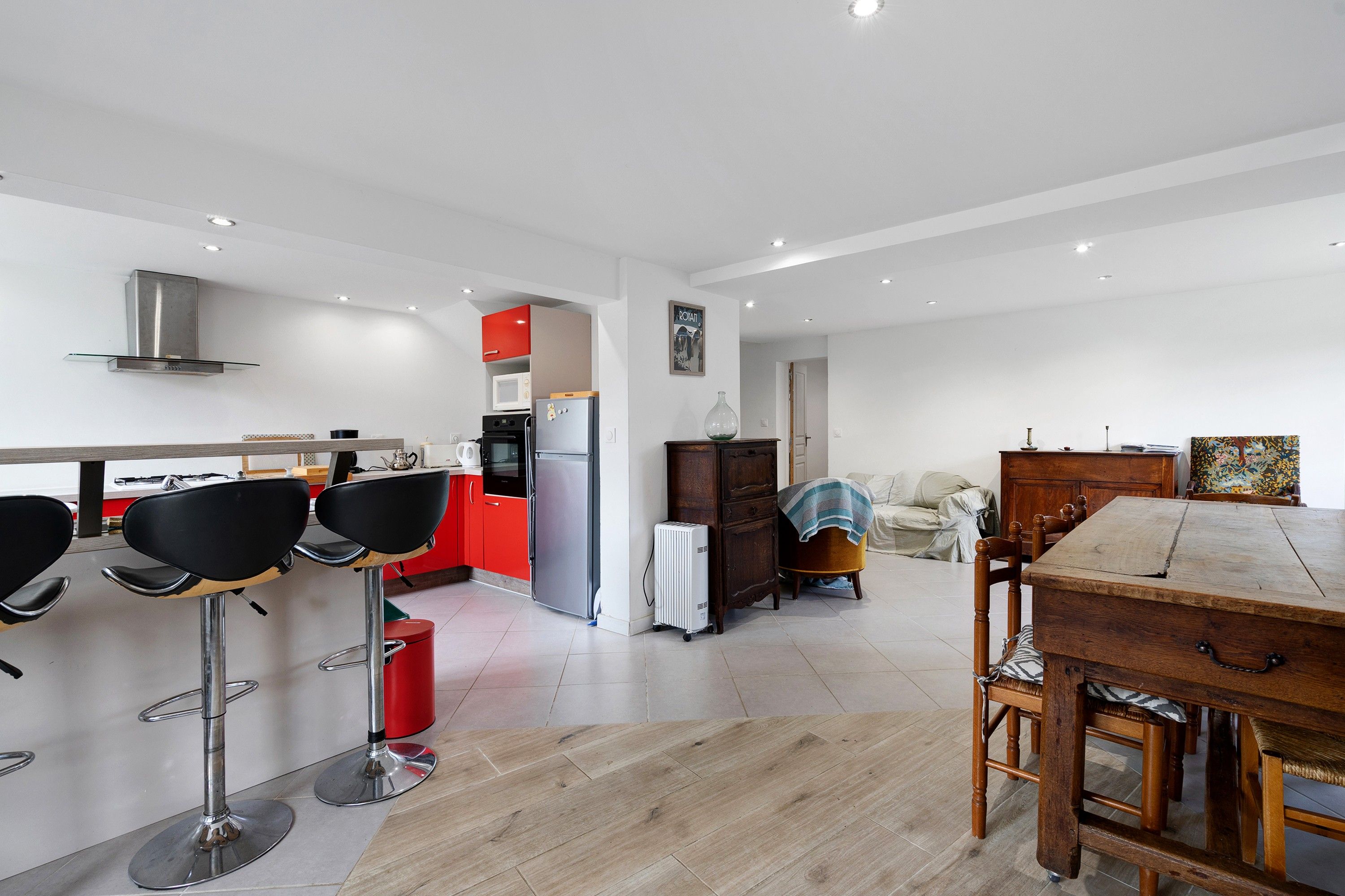 A modern kitchen with a dining area, including a wooden table and chairs, and a red cabinet.