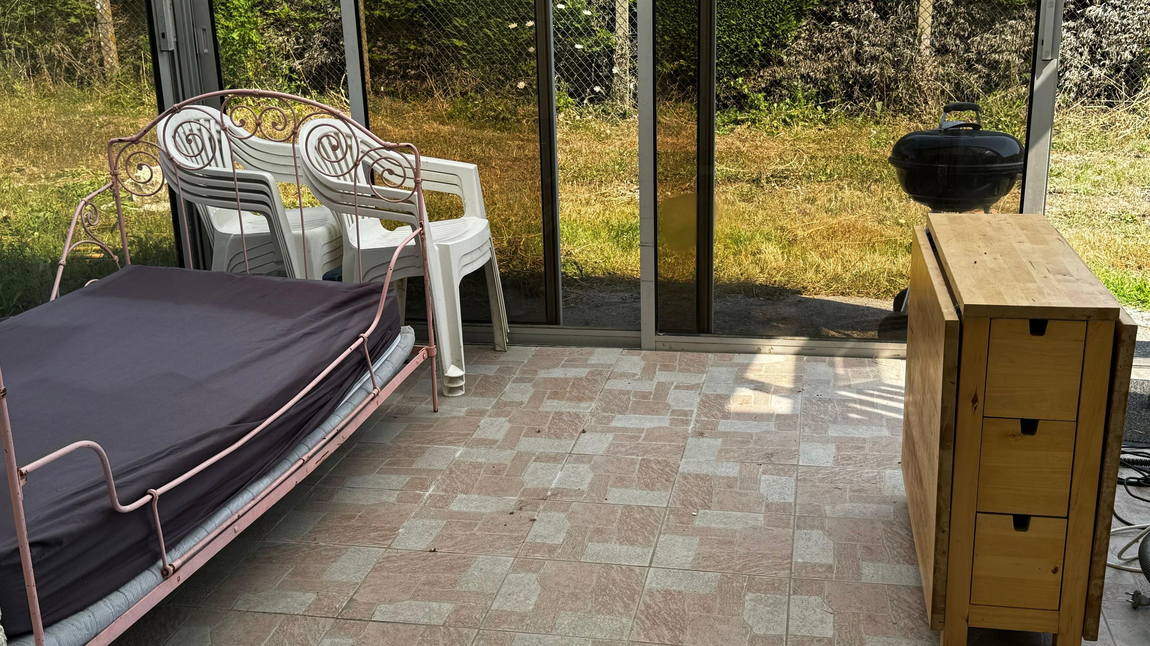 Ein Zimmer mit Bett, Stuhl, Tisch und Fenster.