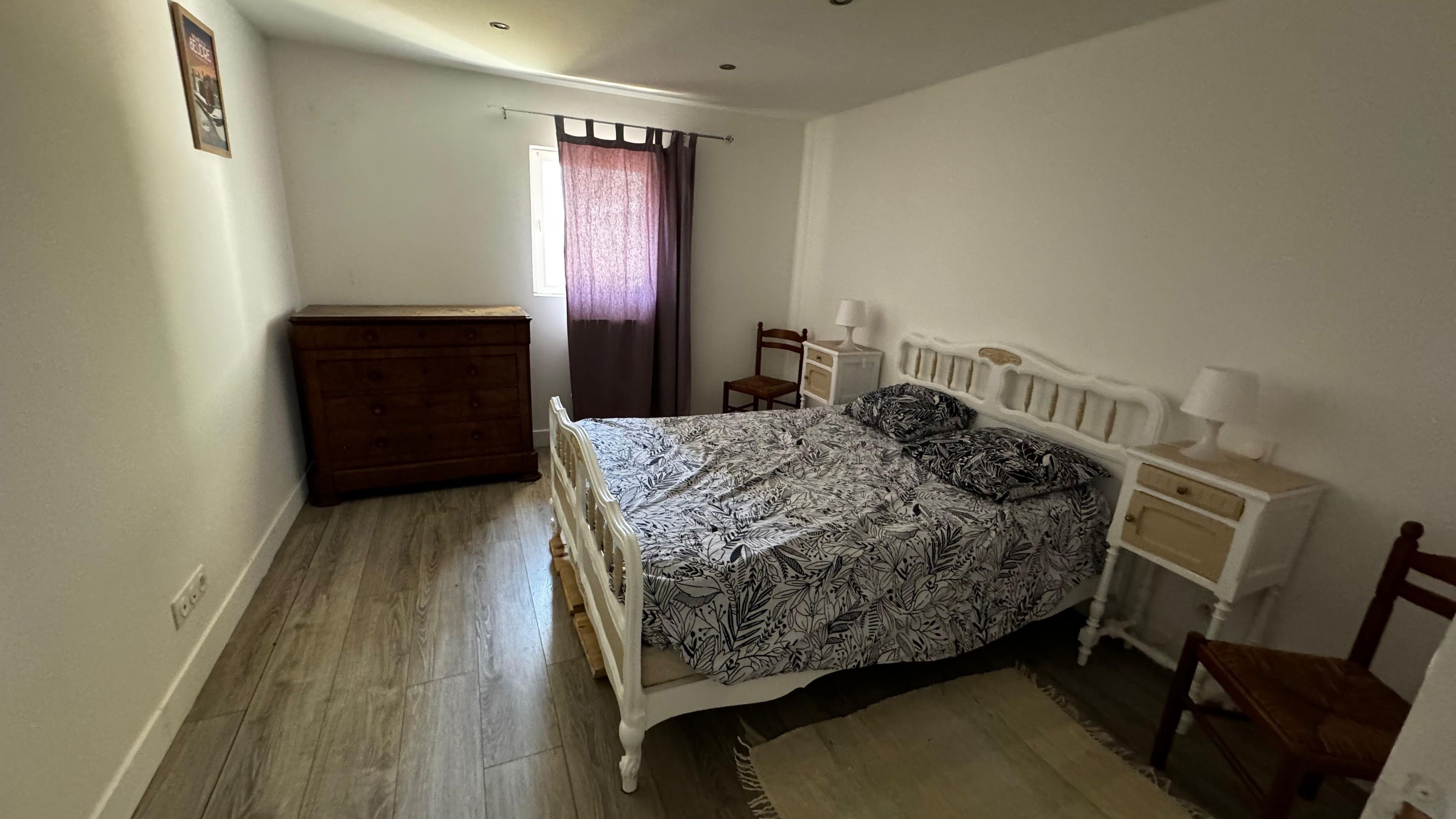 A bedroom with a bed, dresser, chair, and bedside table.