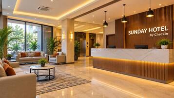 En hotellobby med modern design, inklusive en receptionsdisk, en sittgrupp med soffor och krukväxter.