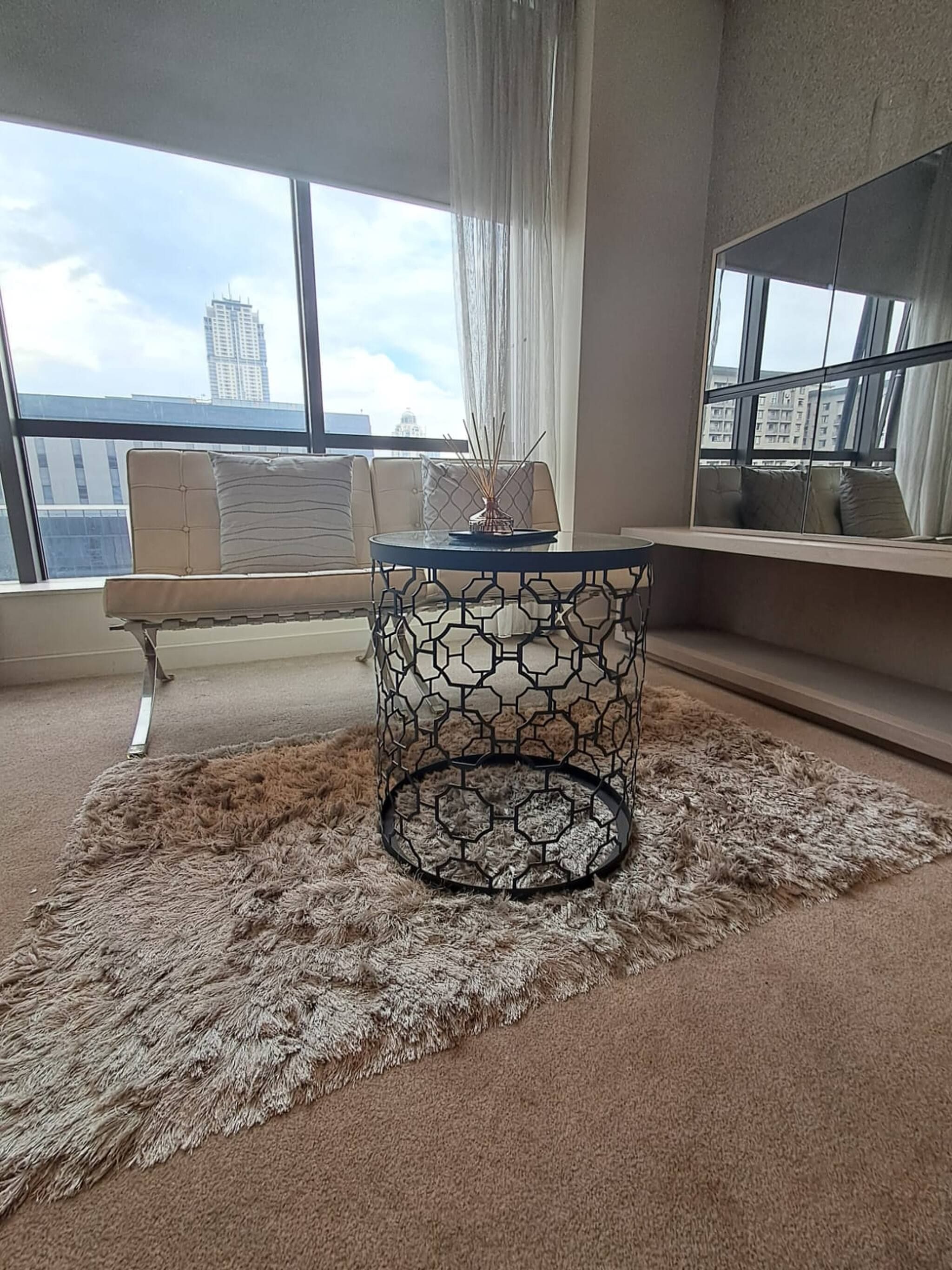 Una habitación con una mesa redonda, un sofá y vistas a edificios a través de amplias ventanas.