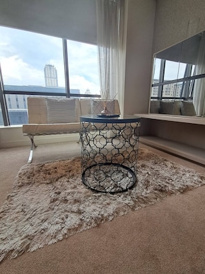 Una habitación con una mesa redonda, un sofá y vistas a edificios a través de amplias ventanas.
