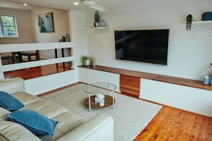 A living room with a sofa, coffee table, TV, and wooden flooring. - The Perfect Family & Furry-Friend Getaway in Heart of Charlestown (Charlestown)