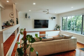 A modern living room with a large window, a flat-screen TV mounted on the wall, and a wooden staircase. - The Perfect Family & Furry-Friend Getaway in Heart of Charlestown (Charlestown)