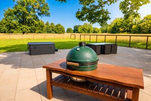 Eine Außenpatio mit einem Holztisch und einem grünen Grill.
