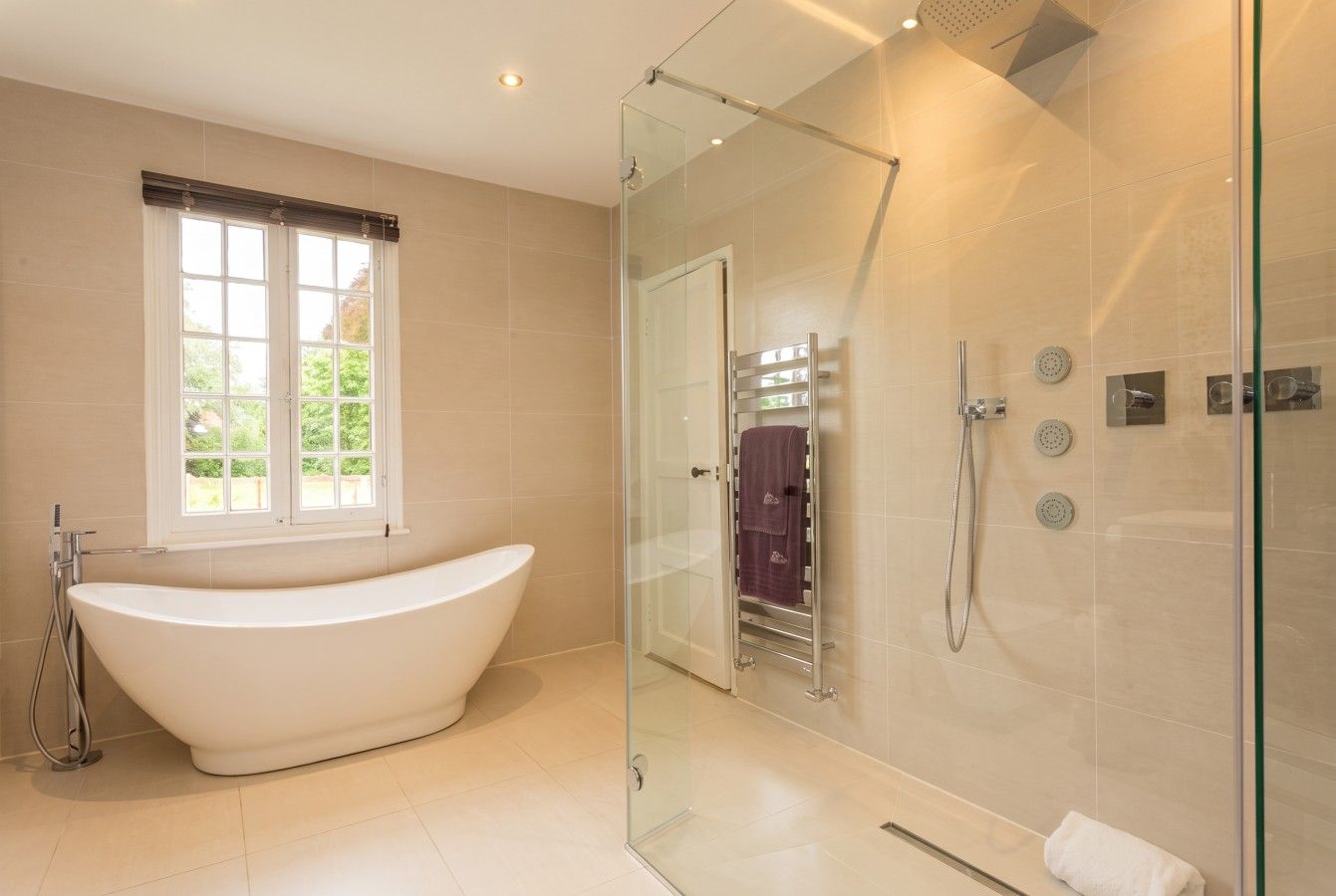 Porcelanosa bathroom with a freestanding bath and walk-in rain shower.