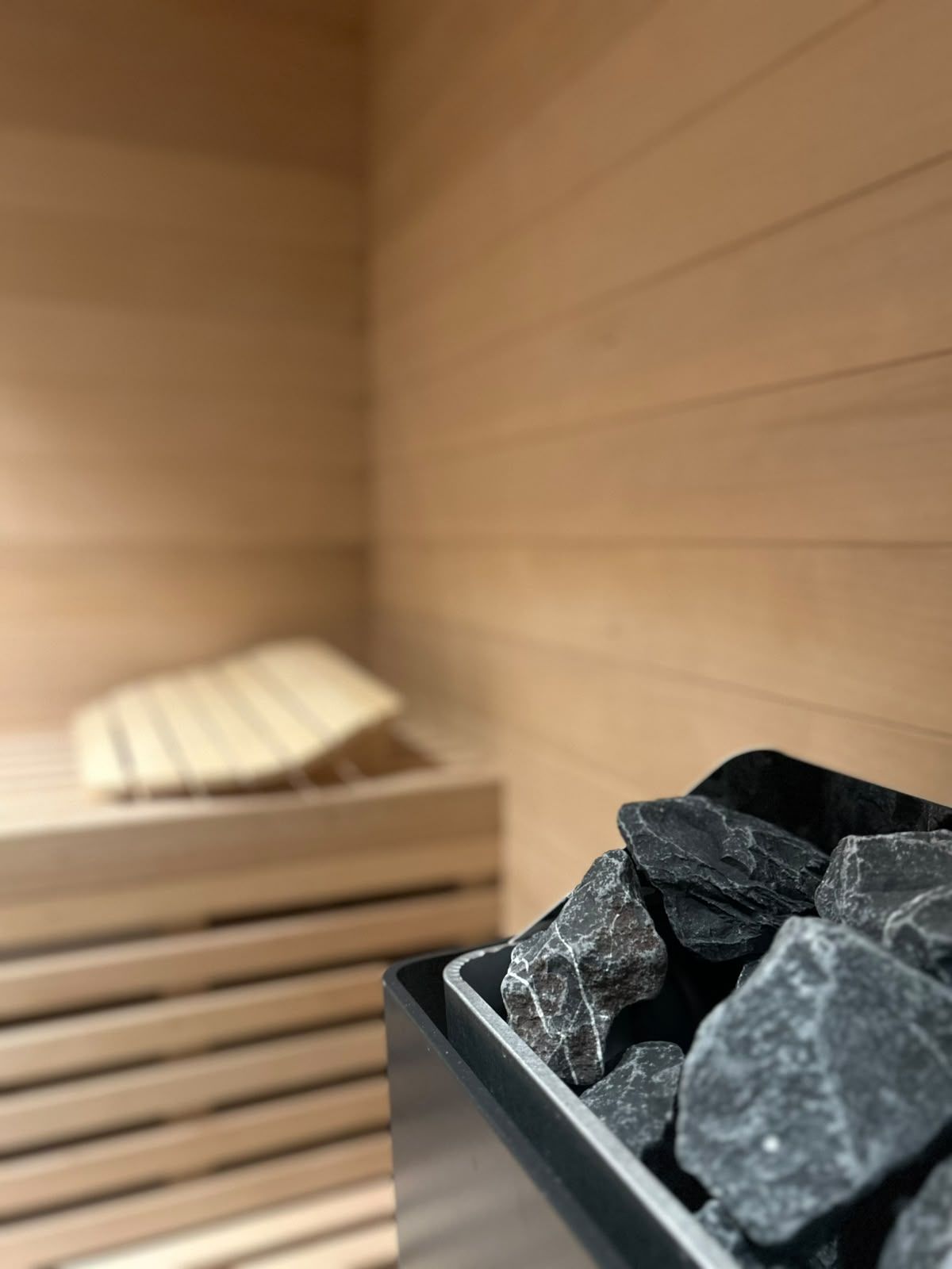 Un intérieur en bois avec un récipient noir contenant des pierres noires.