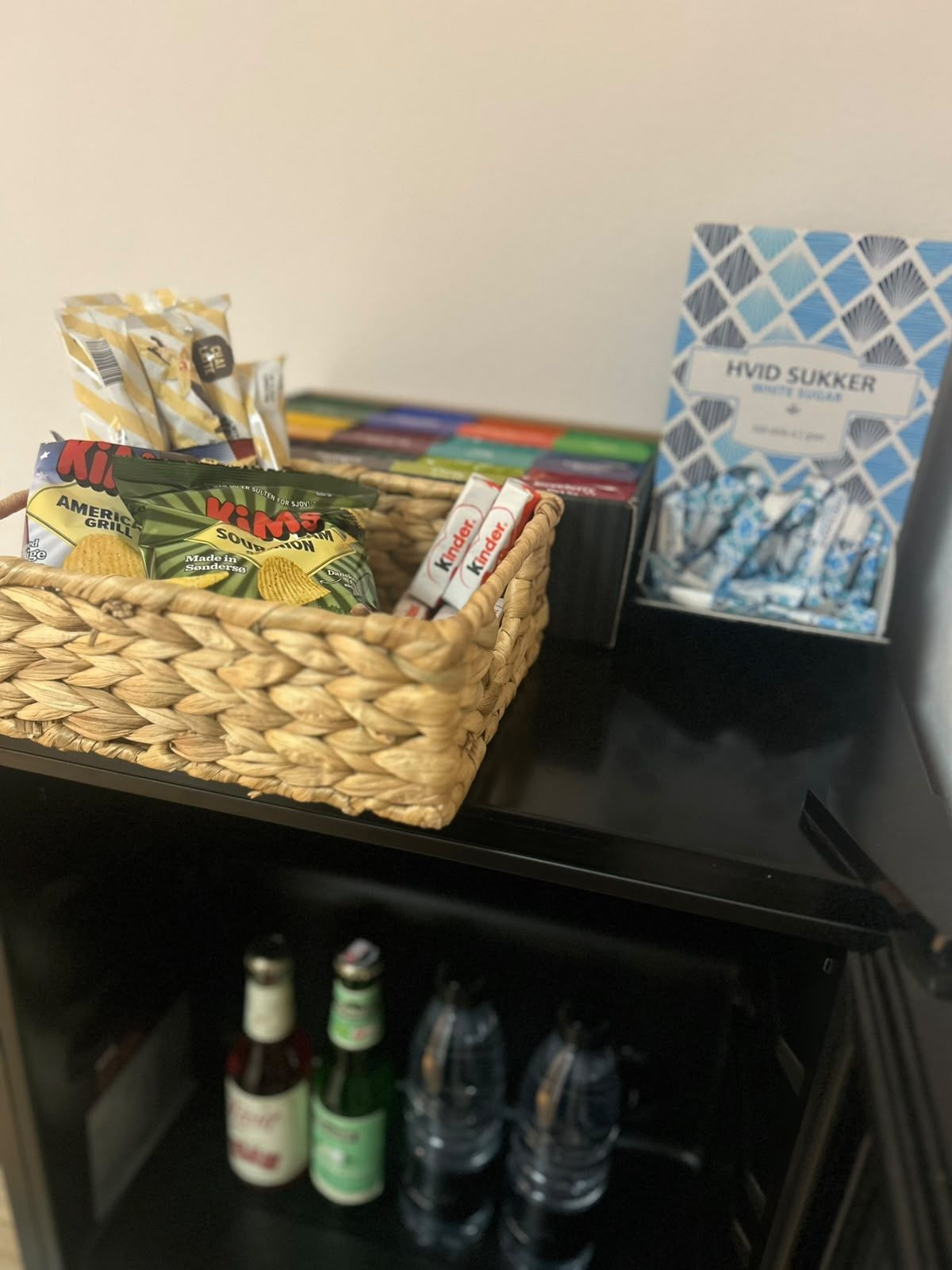 A basket containing snacks and Kinder chocolate bars on a shelf.