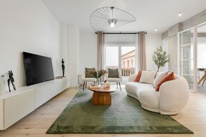 A modern living room with a flat-screen TV, a coffee table, a sofa, and a large window with curtains. - New Listing (Madrid)
