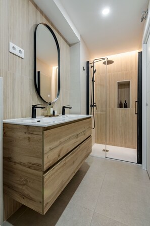 A modern bathroom with a wooden vanity, a large mirror, and a walk-in shower. - New Listing (Madrid)