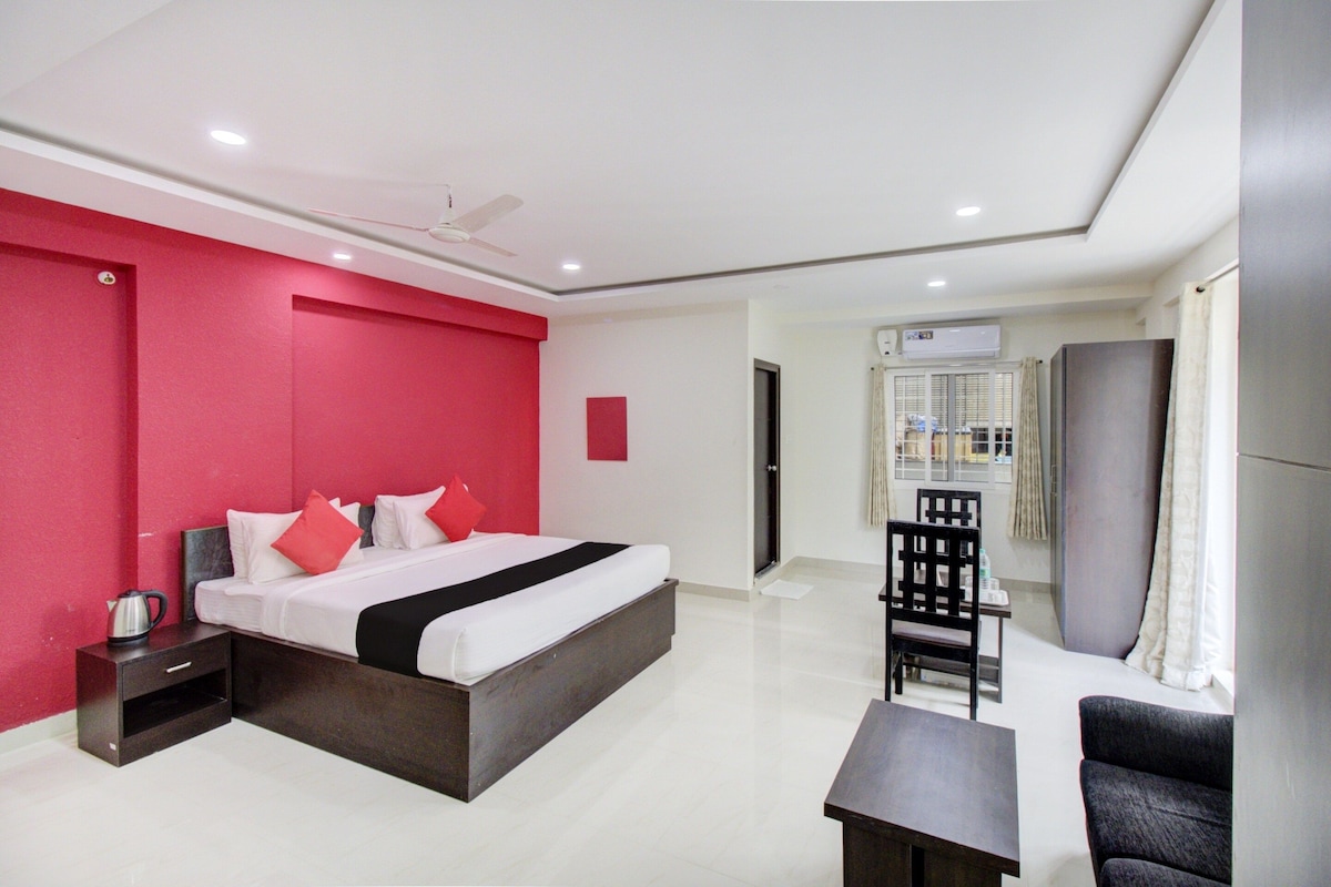 A hotel room with a bed, bedside table, chair, and a small table.