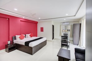 A hotel room with a bed, bedside table, chair, and a small table. - Super Hotel O by OYO 75327 Atithi (Bangalore)