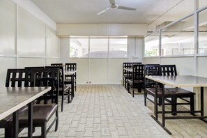 A conference room with tables and chairs, large windows, and a ceiling fan. - Super Hotel O by OYO 75327 Atithi (Bangalore)