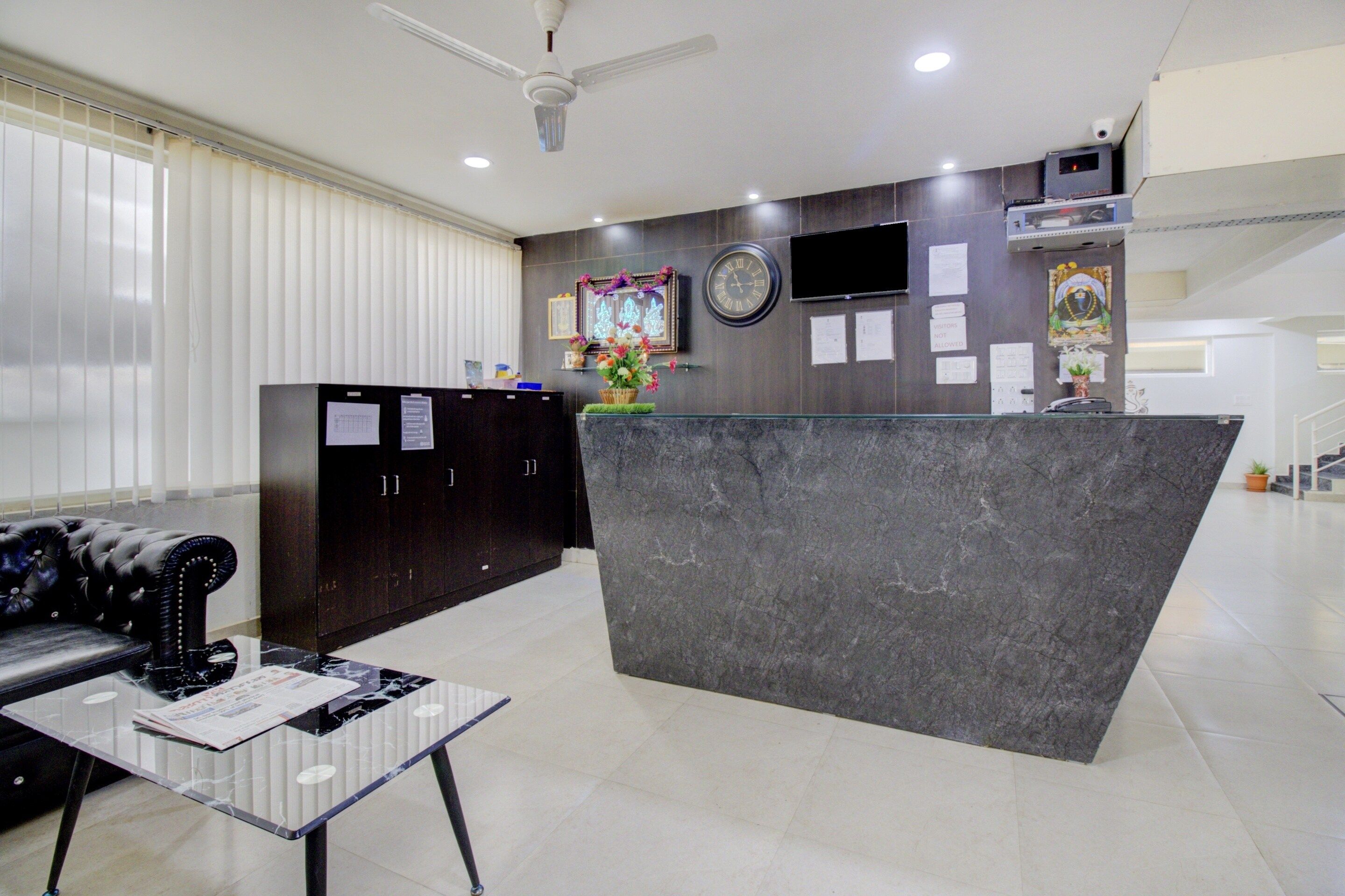 A reception area with a marble counter, a black leather sofa, and a glass coffee table.