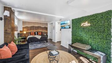 A modern living room with a sofa, a coffee table, and a green wall with a 'good vibes' sign.