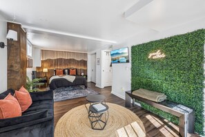 En moderne stue med en sofa, et sofabord og en grøn væg med et skilt, der siger 'good vibes'.