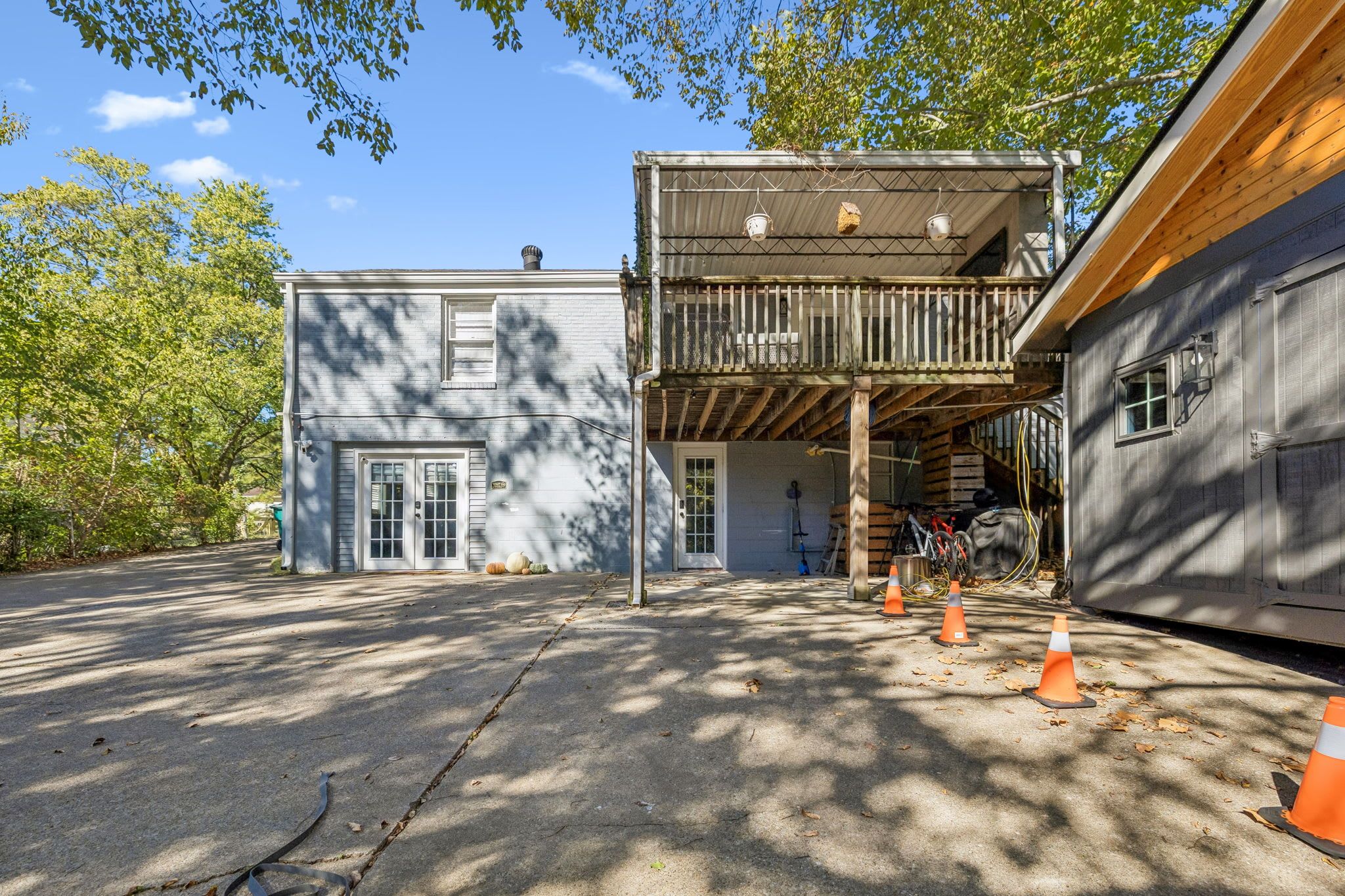 En toetagers bygning med balkon, garage og indkørsel med orange kegler.