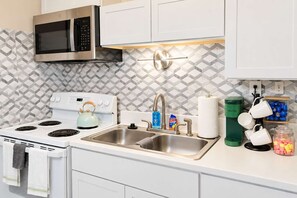 A kitchen with a stove, microwave, sink, and a coffee maker. - Exclusive Queen Suite near Downtown Louisville! (Clarksville)
