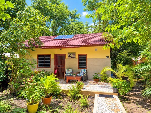 A house with a tiled roof, solar panels, and a garden with various plants.