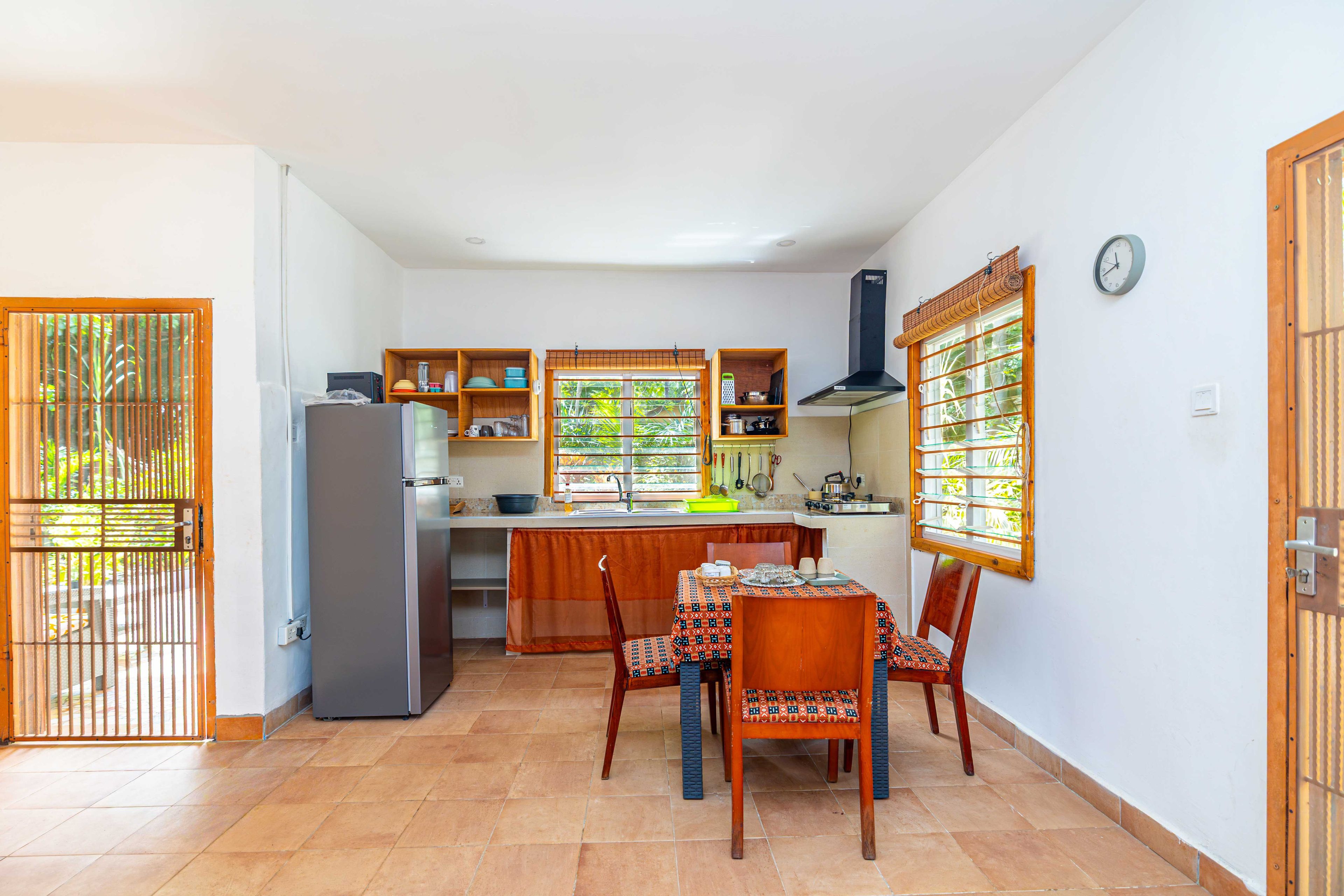 Una cocina compacta con comedor, que incluye un refrigerador, armarios de madera y piso de cerámica.