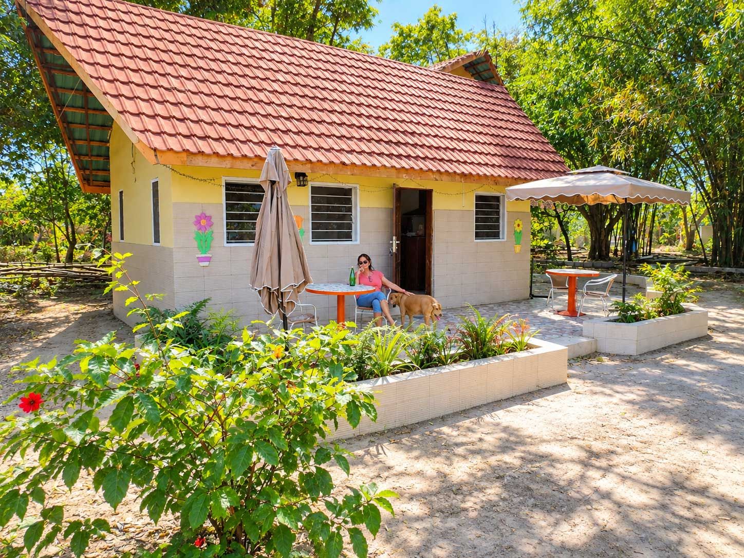 A house with a tiled roof, a patio with a table and chairs, and a dog.