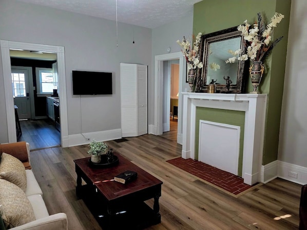 Una sala de estar con chimenea, televisor y comedor con mesa y sillas.